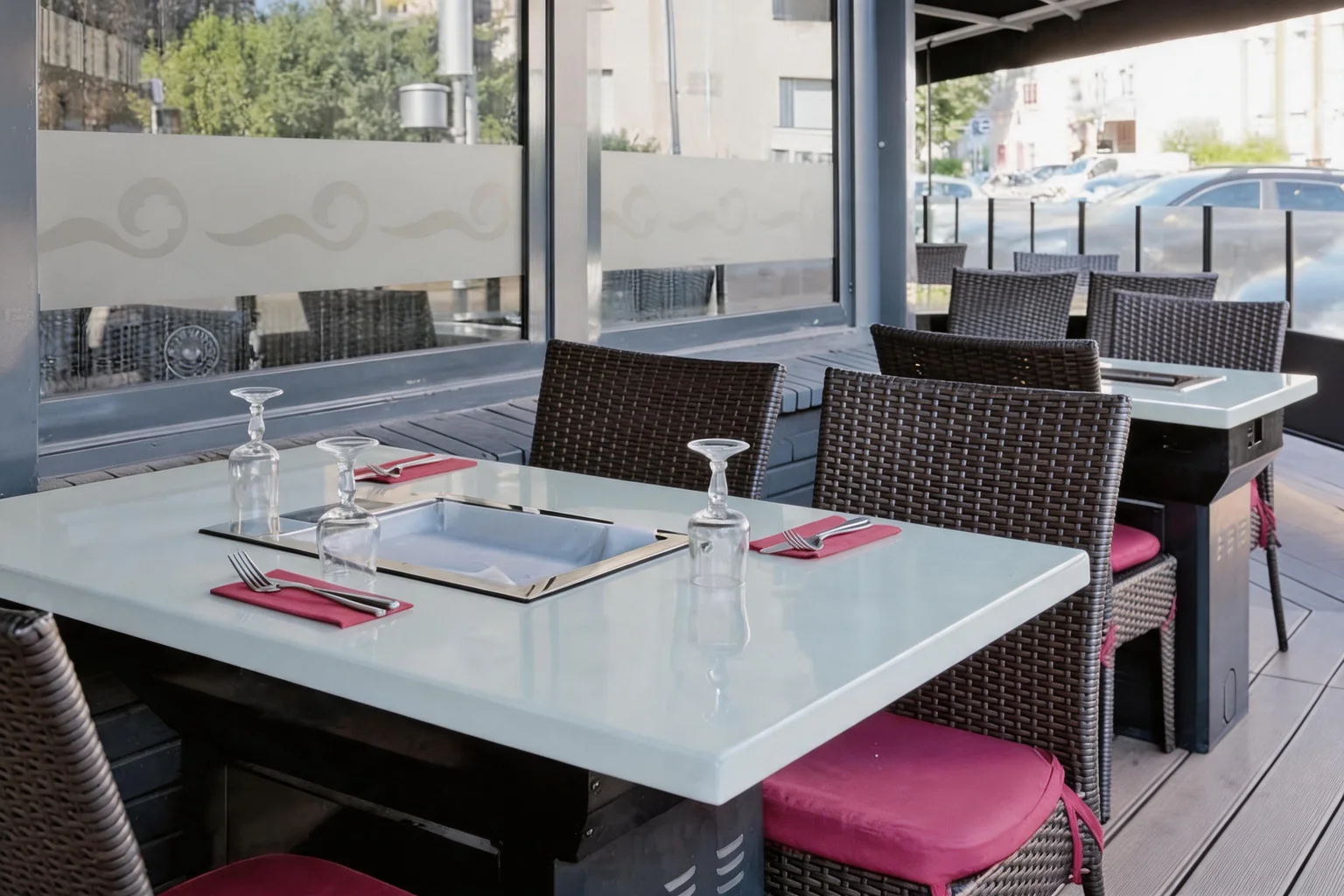 White table with a built-in griddle, woven chairs with fuchsia cushions