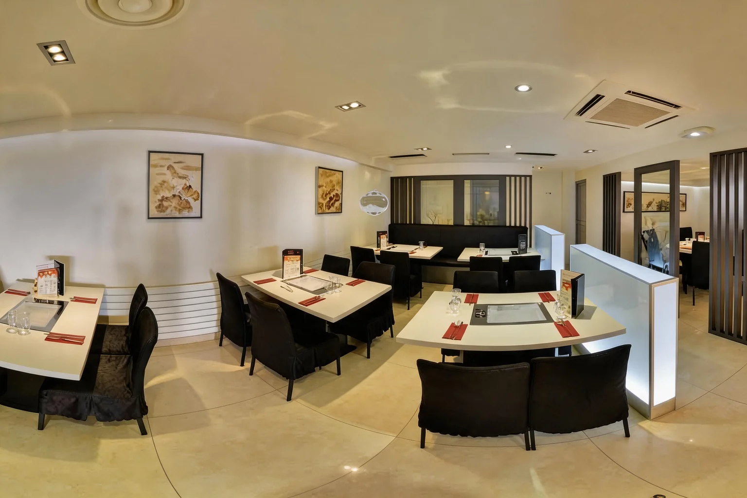 Dining room with laid tables, black chairs and paintings on the wall